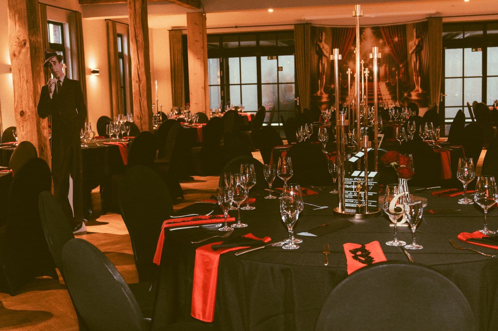 Festsaal mit schwarz-rot eingedeckten Rundtischen und Filmdekoration für einen Galaabend
